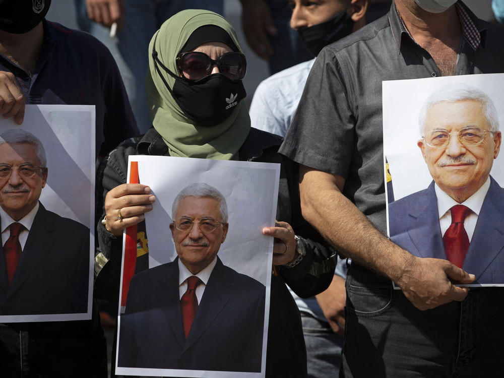 Palestinians wearing protective face masks amid the coronavirus pandemic hold pictures of Palestinian Authority President Mahmoud Abbas during a September rally in the West Bank town of Tubas.