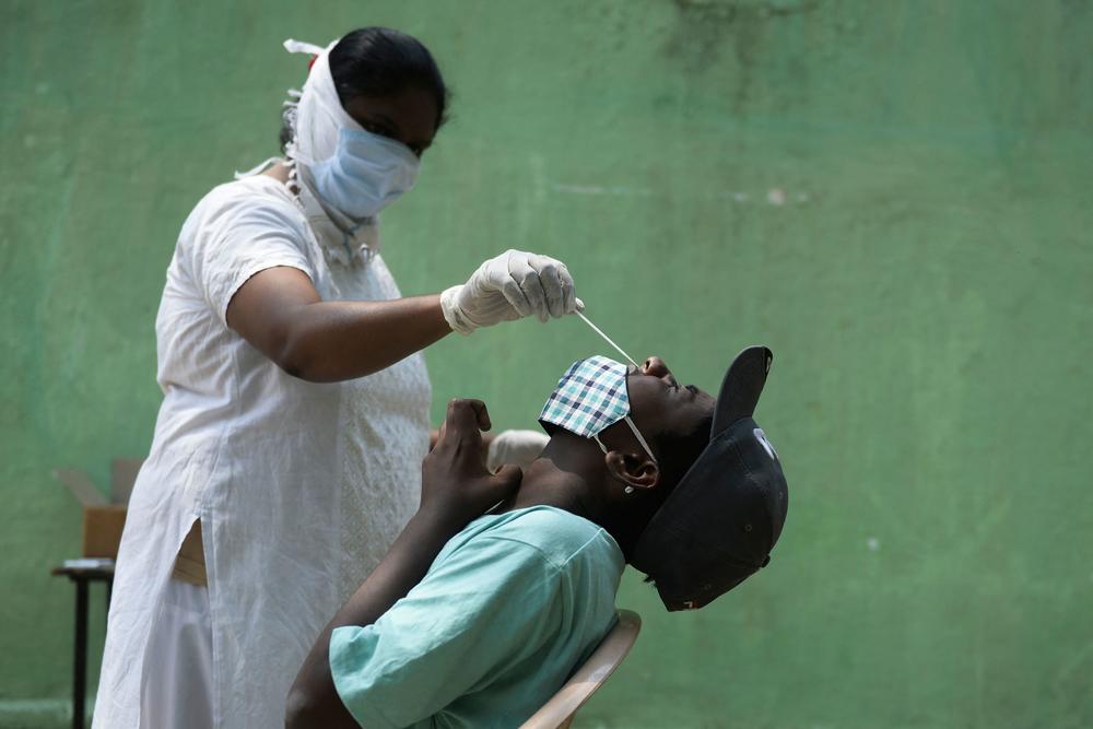 A health worker collects a nasal swab sample from a man to test for the coronavirus in Hyderabad. Tests are in short supply in India, where the Health Ministry confirmed 386,453 infections Friday — more than any country on any day since the pandemic began.