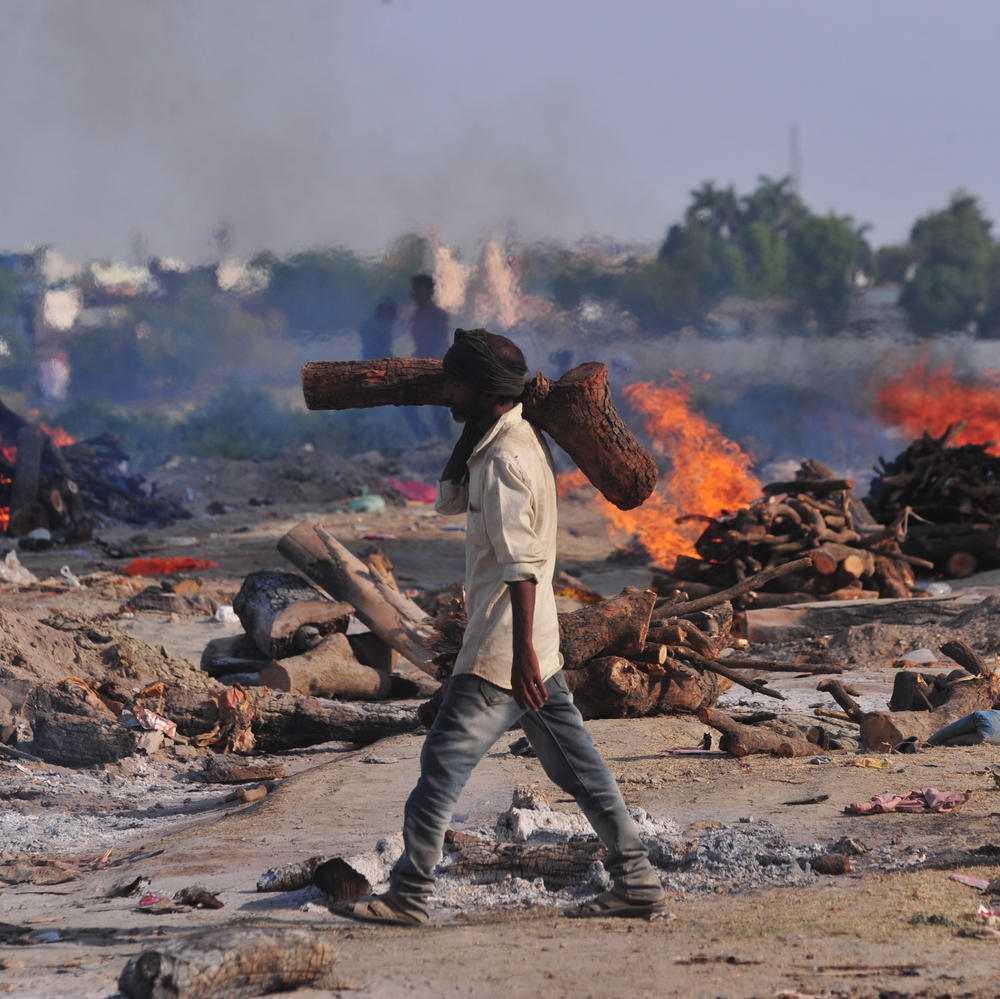 A worker carries wood to a mass cremation site on the banks of the Ganges River in Allahabad on Tuesday.