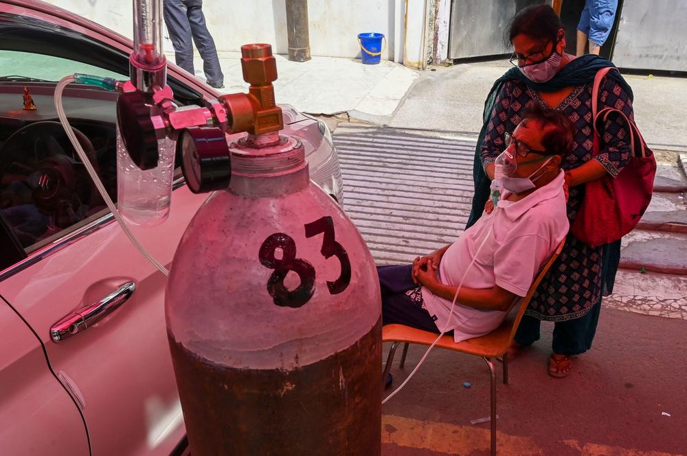 A COVID-19 patient breathes with the help of oxygen at a tent installed along a roadside on Wednesday in Ghaziabad.