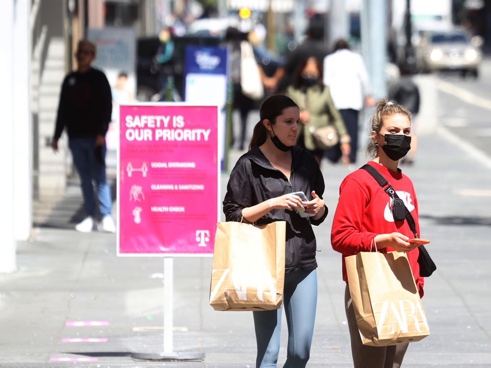 Pedestrians carry shopping bags as they walk through the Union Square shopping district on April 15 in San Francisco. Data on Friday showed personal income jumped 21.1% last month, in what was the largest increase on record.