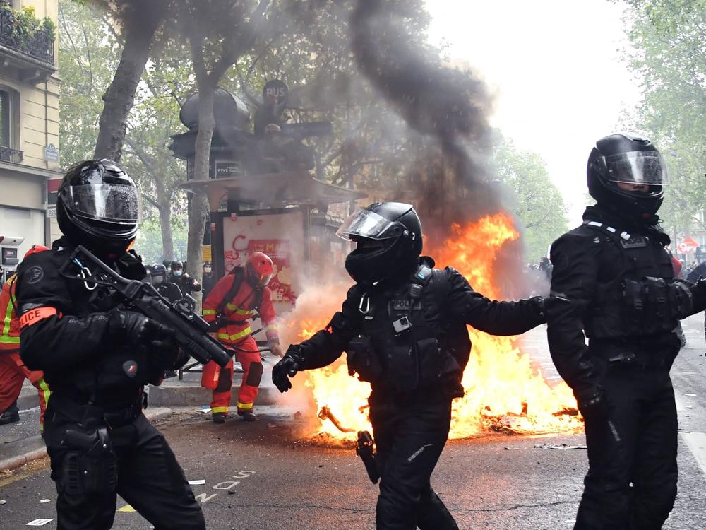 Police officers walk near a fire burning in the street during May Day protests in Paris on Saturday.