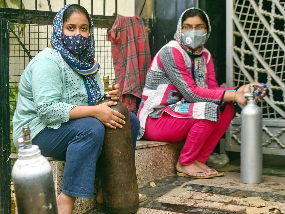 India has reported more than 20 million coronavirus cases, adding more than 2.6 million new cases in the past week alone. Here, women wait to refill empty oxygen cylinders in New Delhi. Oxygen shortages are blamed for deaths at even the best-equipped urban hospitals in India.