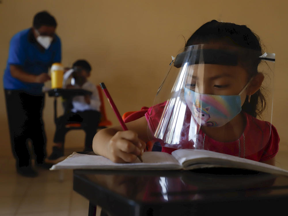 Wearing a mask and a face shield to curb the spread of the coronavirus, 10-year-old Jade Chan Puc writes in her workbook during the first day of class in Hecelchakán, Campeche state, Mexico, on April 19. On average, schools in Latin America and the Caribbean were closed longer than any in any other region, according to UNICEF.