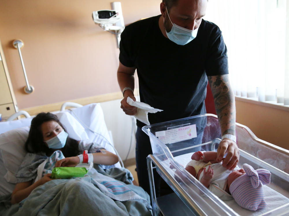 Matthew Carnes prepares to change diapers for his newborn daughter, Evelina Carnes, as his wife, Breanna Llamas, keeps watch in the postpartum unit at Providence St. Mary Medical Center in Apple Valley, Calif., in March. The U.S. has reported another record low in its birthrate.