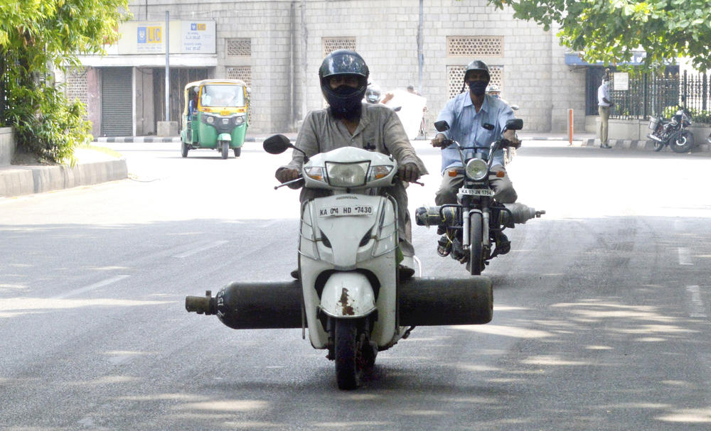 Scooter riders carry oxygen cylinders, hoping to find a source where they can refill the containers, in Bengaluru<strong> </strong>on May 1.
