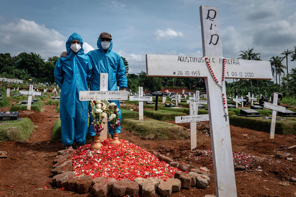 Two men, wearing personal protective equipment, visit the grave of a relative in a public cemetery, reserved for suspected COVID-19 victims, in December in Jakarta, Indonesia.