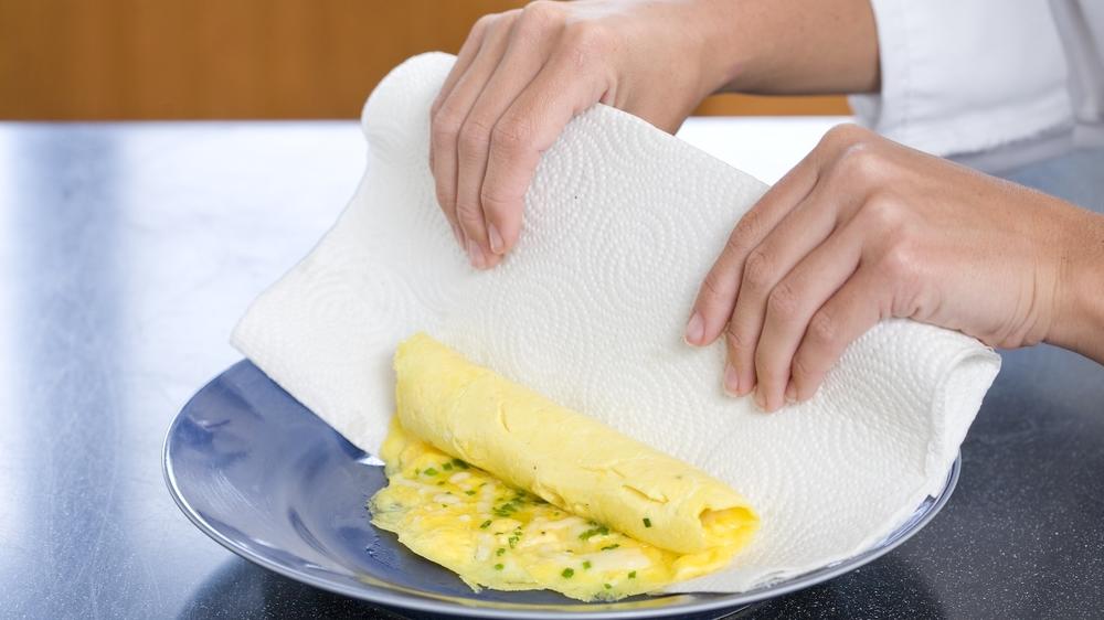 Slide the omelet from the pan onto your plate and a paper towel, then lift the towel so that the omelet rolls on itself.