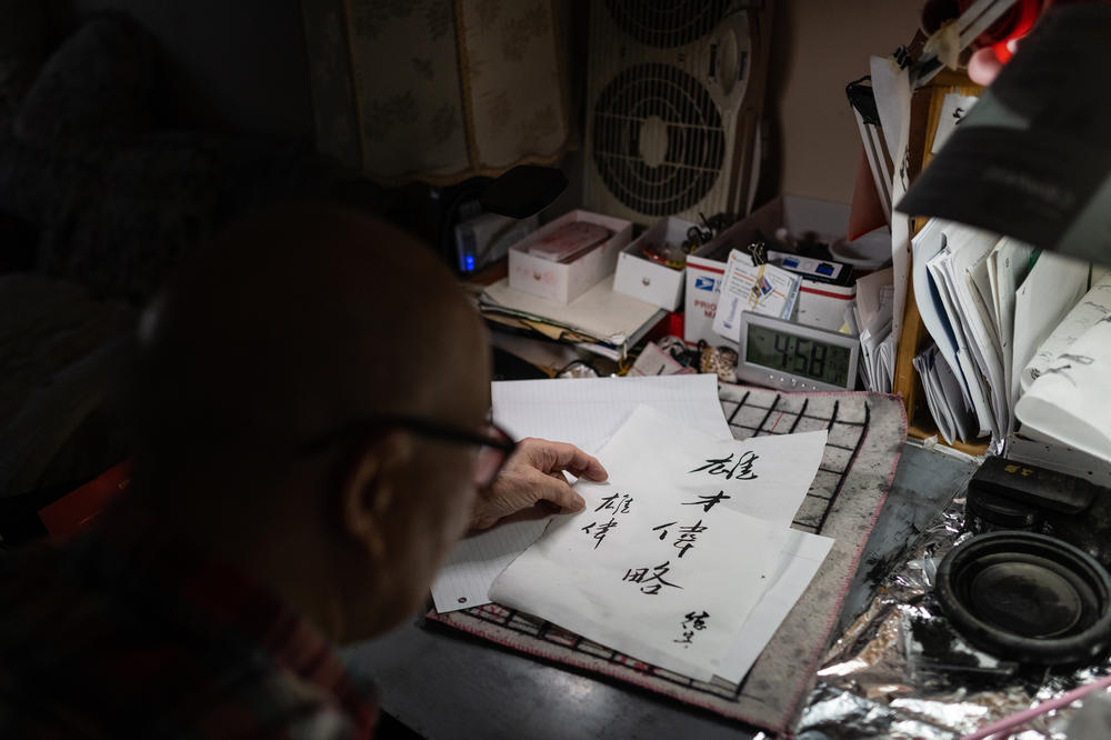 Dock Lee, 90, adds his signature to a calligraphy script with the meaning of Eric Lee's name, 