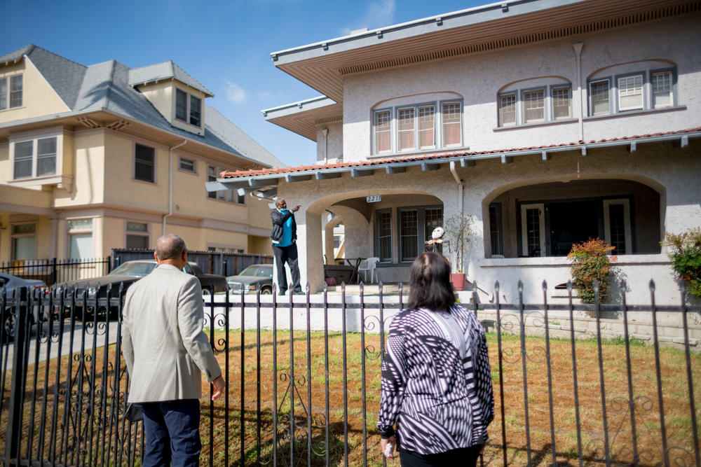 Outside the former home of their grandfather, Norman Houston, Ivan Houston and Kathi Houston-Berryman speak with a current resident who points next door to where <em>Gone with the Wind </em>actress Hattie McDaniel once lived.