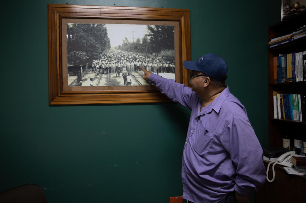 Ismael Moreno Coto, better known as Padre Melo, a firebrand human rights advocate and Jesuit priest, points to a photograph in his office showing the labor movements that El Progreso has been known for.