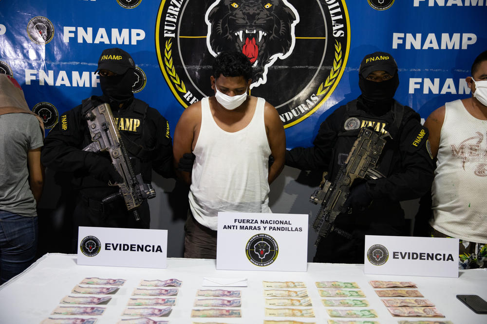 An alleged gang member lowers his head while flanked by two officers of the special anti-gang unit of the Honduran National Police at a news conference in San Pedro Sula after his arrest.