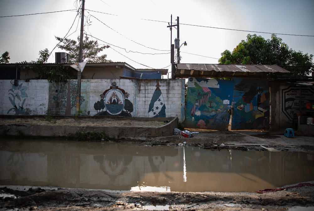 Still water pools outside a public school in the Ciudad Planeta neighborhood of San Pedro Sula, where remains of the 2020 flood have yet to be cleared.