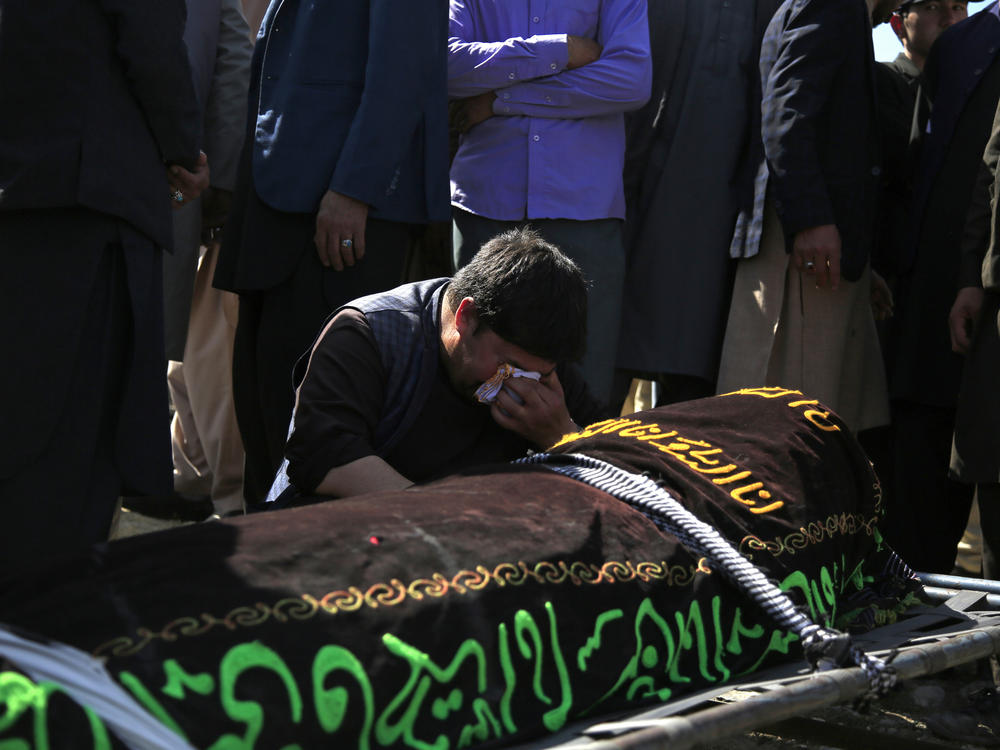 A man cries over the body of a victim of deadly bombings on Saturday near a school, at a cemetery west of Kabul on Sunday. More than 50 were killed in the attack, many of them pupils between 11 and 15 years old. More than 100 were wounded.