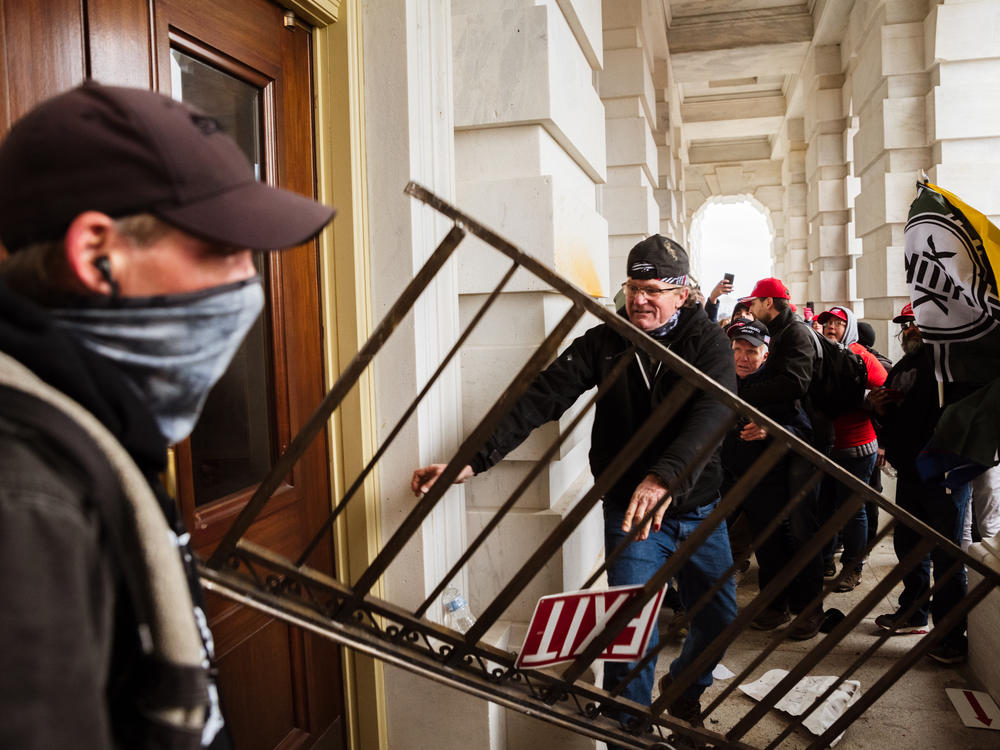 A member of a pro-Trump mob bashes an entrance of the Capitol building in an attempt to gain access on Jan. 6. The U.S. Capitol Police's inspector general has pointed to intelligence failures in the lead-up to the insurrection.