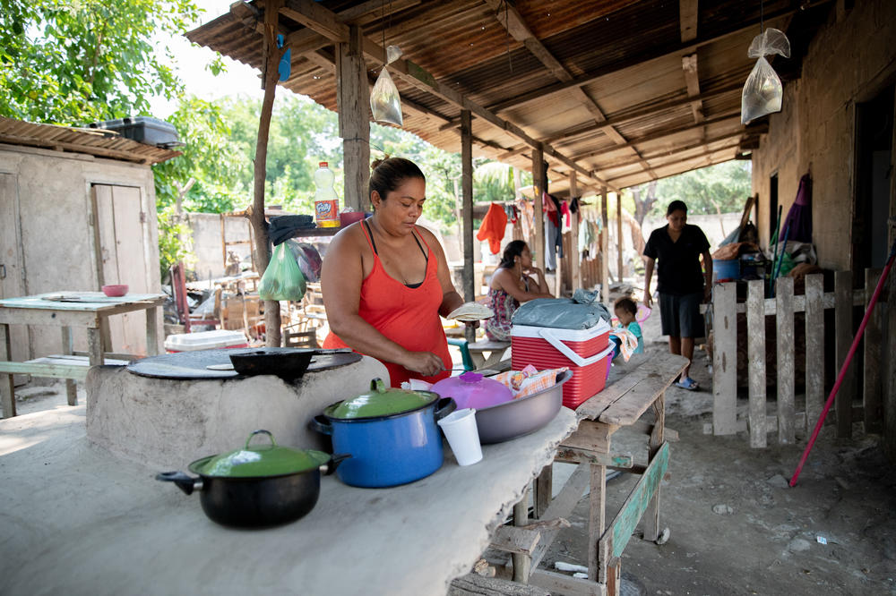 Blanca Marisa Balegas makes tortillas at the Ramos family's new wood-fired stove after the floods disintegrated the old one. Ten family members sleep in the two-room home now. Hurricanes Eta and Iota displaced the family for over five months.