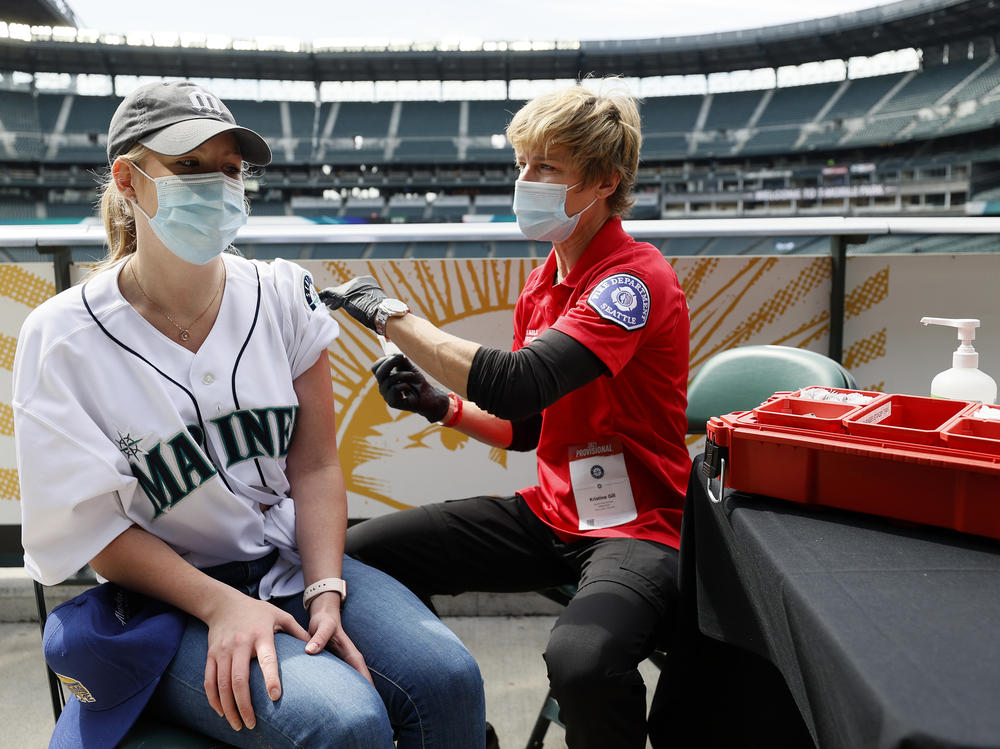 Sydney Porter of Bellevue, Wash., receives her COVID-19 vaccination from Kristine Gill, with the Seattle Fire Department's Mobile Vaccination Teams, before the game between the Seattle Mariners and the Baltimore Orioles at T-Mobile Park on May 5 in Seattle. A late spring COVID-19 surge has filled hospitals in the metro areas around Seattle.