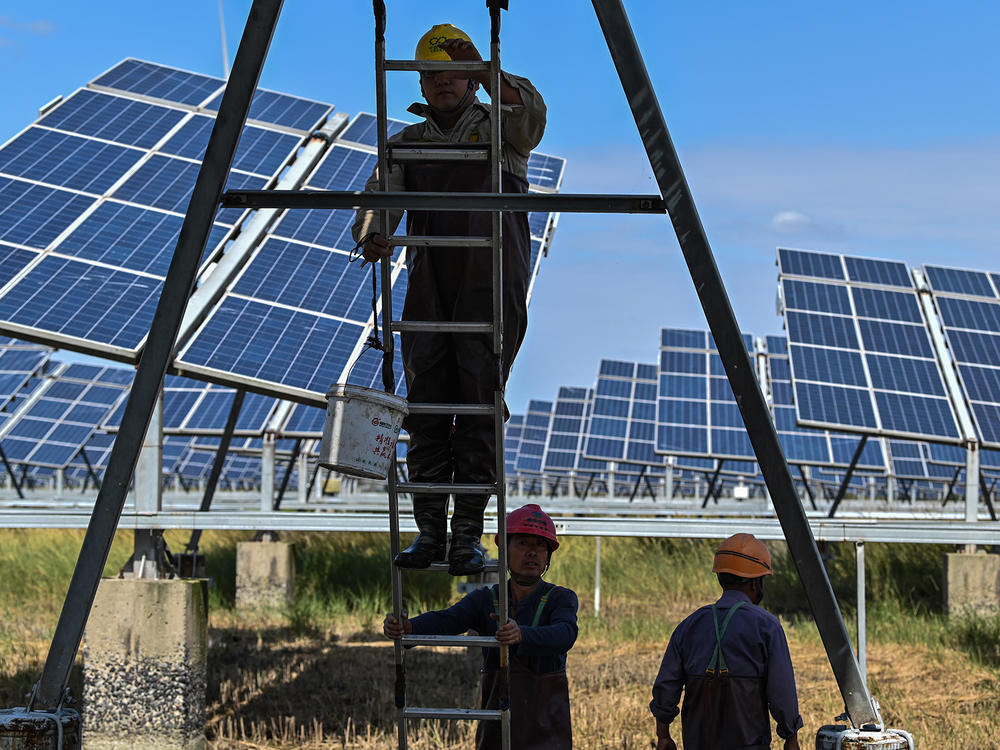 Workers next to solar panels in an integrated power station in Yancheng, China, in October. An unprecedented amount of renewable power came online in the fourth quarter of 2020, according to a new report from the International Energy Agency. China alone added more than 92 gigawatts of capacity, more than triple the amount it added in the fourth quarter of 2019.