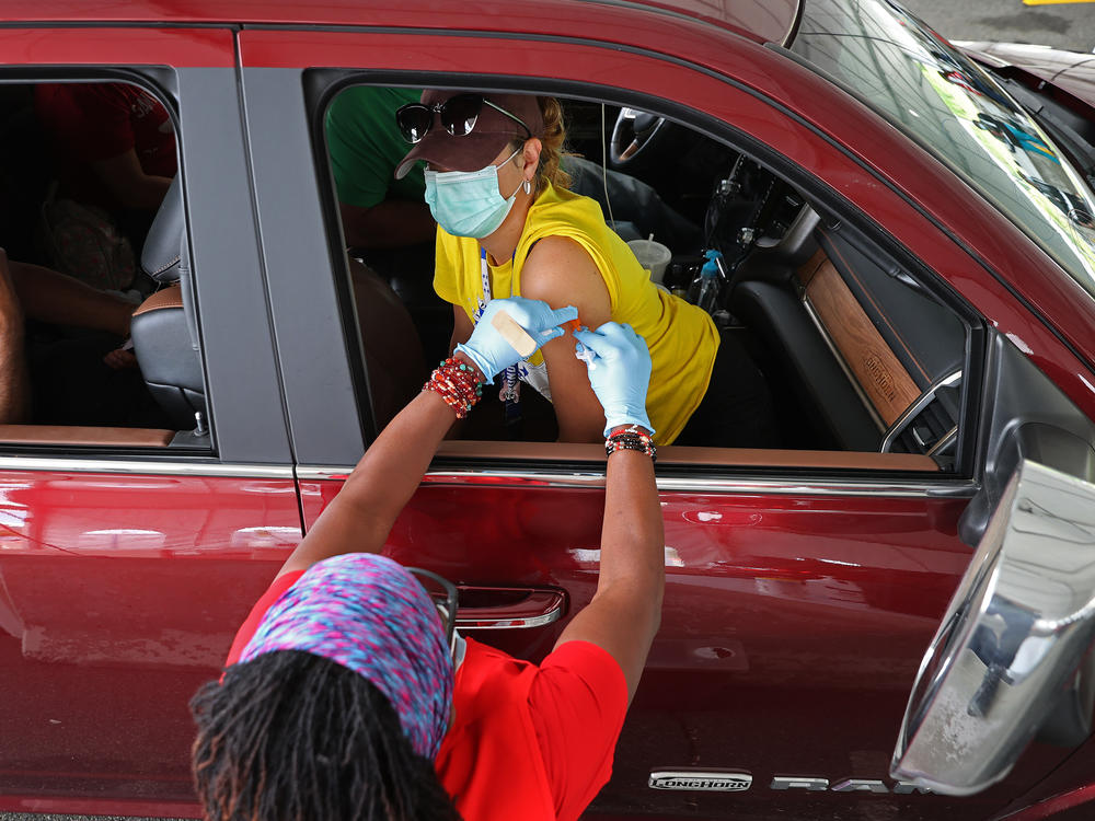 People who need help getting to a vaccination site will be able to get free or discounted rides through Uber and Lyft, the White House says. Here, a woman receives her first dose of the Pfizer vaccine at a mass vaccination site in Aberdeen, Md., after getting a ride to the site from her landlord.