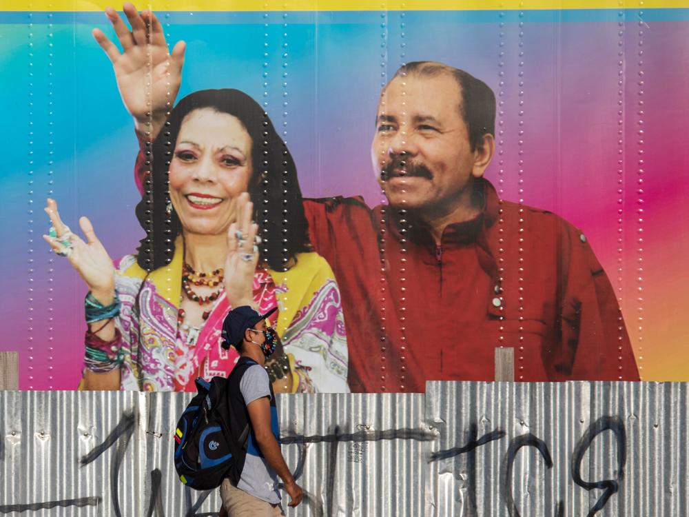 A man walks by a mobile health clinic displaying a picture of Nicaraguan President Daniel Ortega (right) and his wife and vice president, Rosario Murillo, in Managua on April 14, 2020. The government claims to be successfully combating the pandemic but health workers and critics say the toll is likely higher.