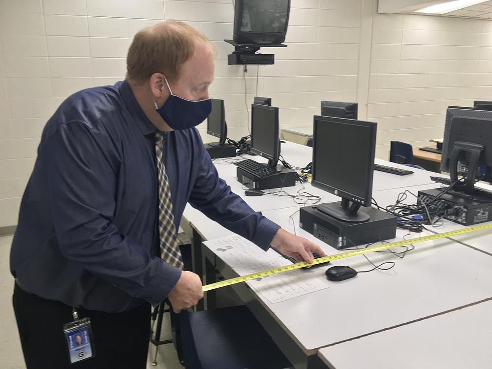 Gaylord High School principal Chris Hodges measures the space between seats in a yearbook class. A student in the class tested positive for covid, and Hodges is working with the local health department to trace people who might have been exposed to her at school.