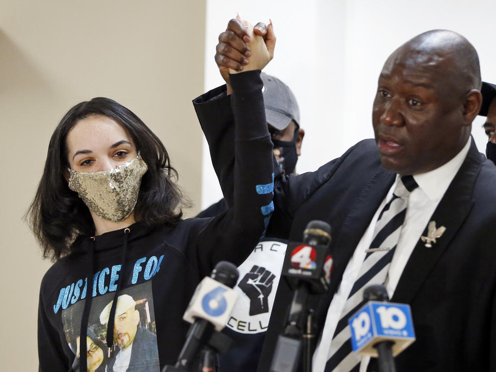 Karissa Hill, daughter of Andre Hill, raises hands with Benjamin Crump, the civil rights attorney representing Hill's family, at a news conference in February after former Columbus police officer Adam Coy was charged with murder in Hill's death.