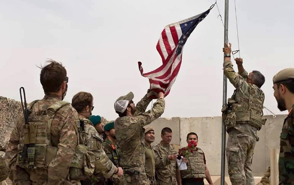 The U.S. flag is lowered as American and Afghan troops attend a handover ceremony at Camp Anthonic in the southern province of Helmand on May 2. After 20 years of war in Afghanistan, U.S. forces now number just a few thousand, down from a peak of more than 100,000 a decade ago.