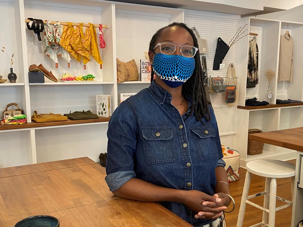 Nicole McGrew, wearing a mask by the designer N'omose Couture, says she'll require customers to mask up in her store for a short time longer.