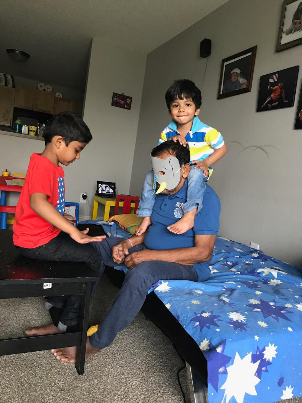 Sudheer Kumar Pradhan wears an elephant mask while playing with his grandchildren in an undated family photo. He was 78 when he died of COVID-19.