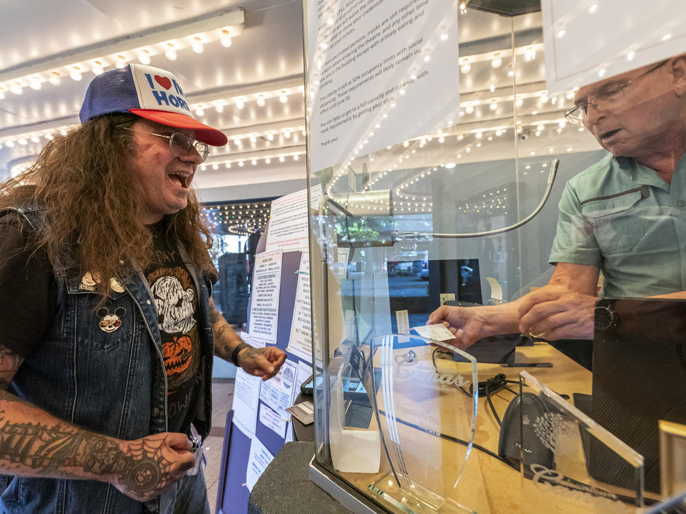 Darren Ford (left) reacts to the new mask guideline while presenting his vaccine card at Liberty Theatre on May 14 in Camas, Wash. Gov. Jay Inslee announced last Thursday that the statewide mask mandate would no longer apply to fully vaccinated adults.