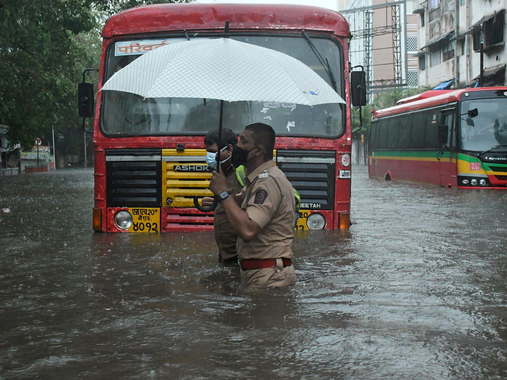 A police officer helps a public transport driver cross a flooded street caused by heavy rain from Cyclone Tauktae in Mumbai.