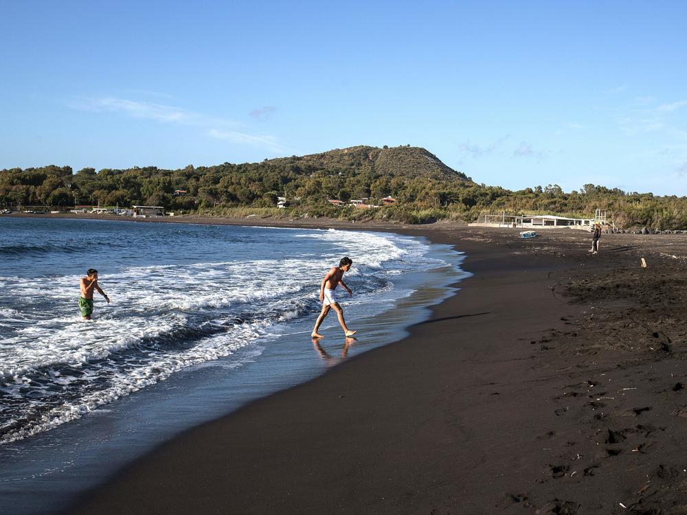 The European Union is poised to open travel to more visitors after ambassadors approved changes to travel restrictions Wednesday. Here, people walk out of the sea last week on Italy's volcanic island of Vulcano.