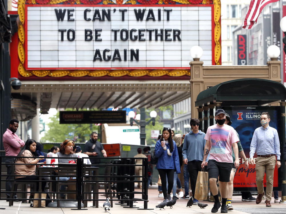 People walk near the Chicago Theatre on Tuesday in the city's Loop community. The Centers for Disease Control and Prevention eased its guidelines on the wearing of masks, saying fully vaccinated Americans don't need to cover their faces anymore in most settings. Will it encourage the unvaccinated to get their shots?