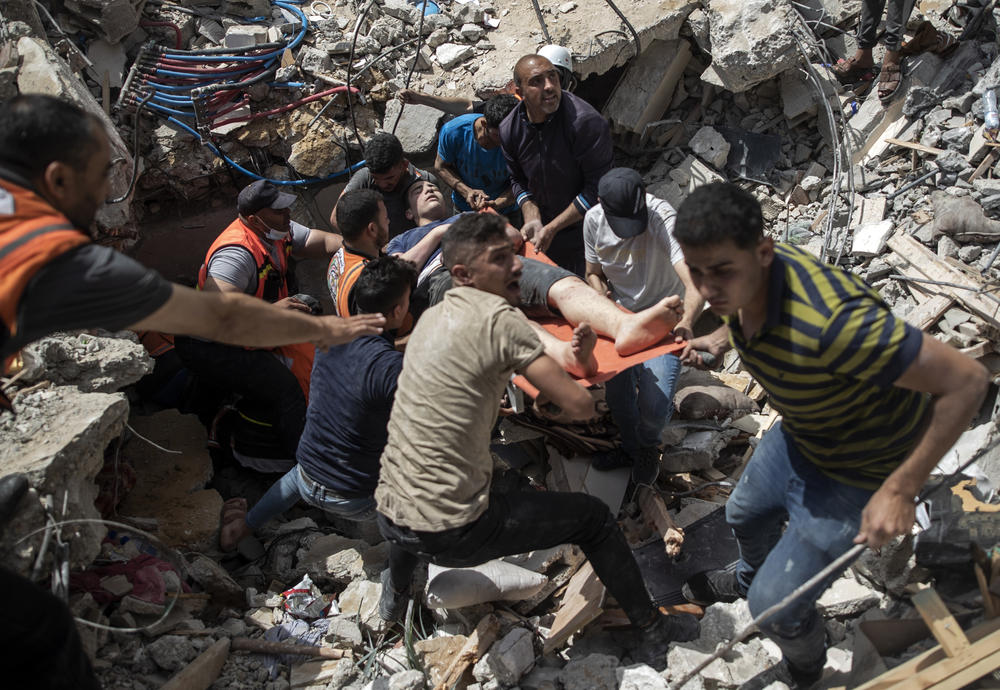 Palestinians rescue a survivor from the rubble of a destroyed residential building following Israeli airstrikes Sunday in Gaza City. Access to hospitals remains a challenge in Gaza.