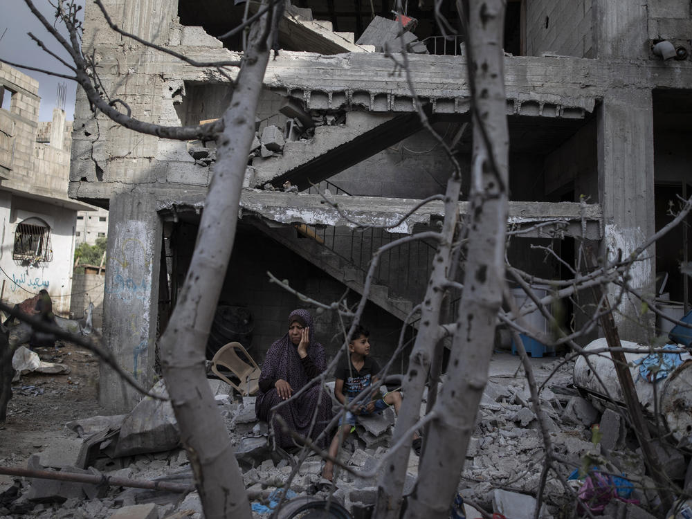 A Palestinian woman sits with her son in front of her destroyed house in the town of Beit Hanoun, northern Gaza Strip, to which she returned following a cease-fire reached after an 11-day war between Gaza's Hamas rulers and Israel.