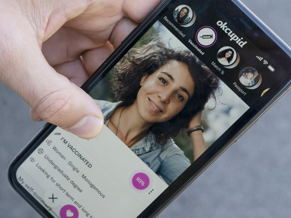 A sample page on the OkCupid app is held for a photograph showing the 