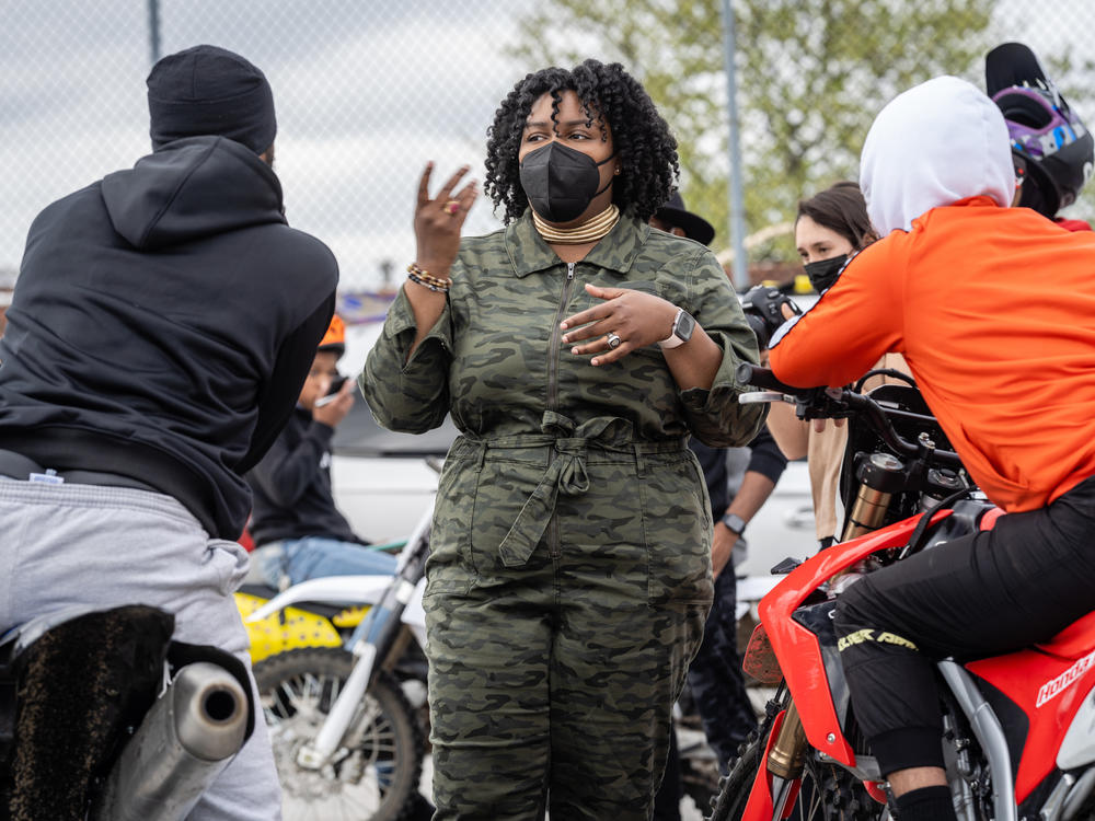 Brittany Young, CEO and founder of the nonprofit B-360, speaks with a couple of people from the neighborhood, who heard the dirt bikes and came to the parking lot to ride themselves.