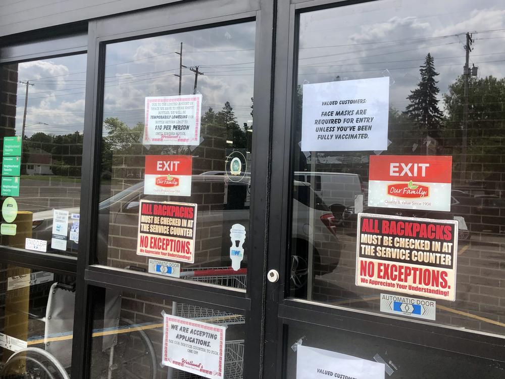 A sign on the front doors of Westlund's Apple Market in Lansing, Mich., asks customers to wear a mask unless they are vaccinated against COVID-19.