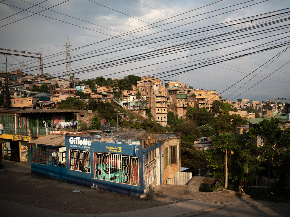 A man cleans a rooftop as the sun sets over the embattled Pedregal neighborhood of Tegucigalpa.