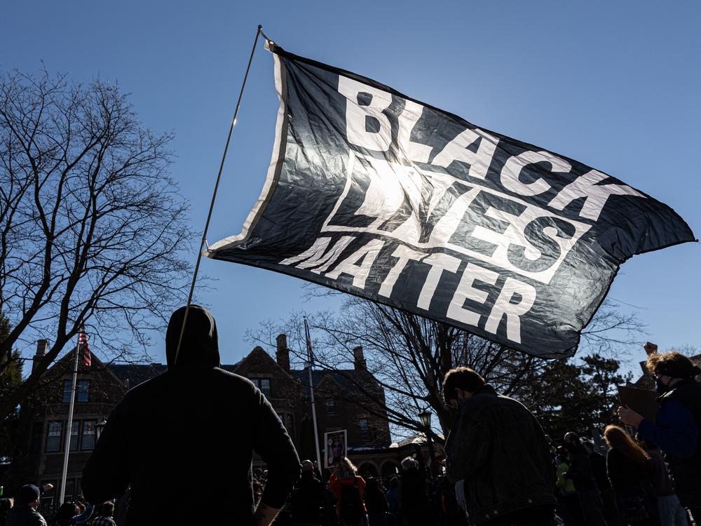 A man holds a Black Lives Matter flag during a March protest in St. Paul, Minn. Support for Black Lives Matter surged after protests following George Floyd's death. Activists charge that disparaging posts targeting BLM are part of an overall effort to undermine the movement and its message.