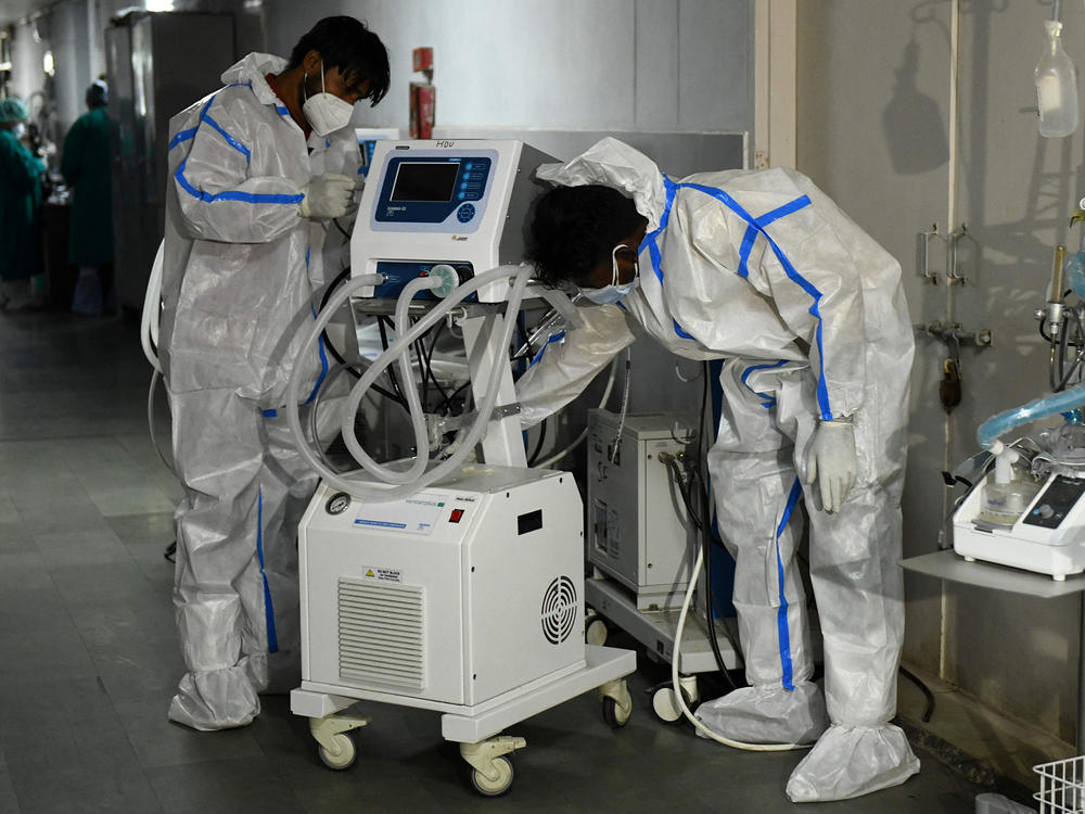 Health workers wearing protective gear place a defunct ventilator machine in the corridor of a hospital in mid-May in Amritsar, India.
