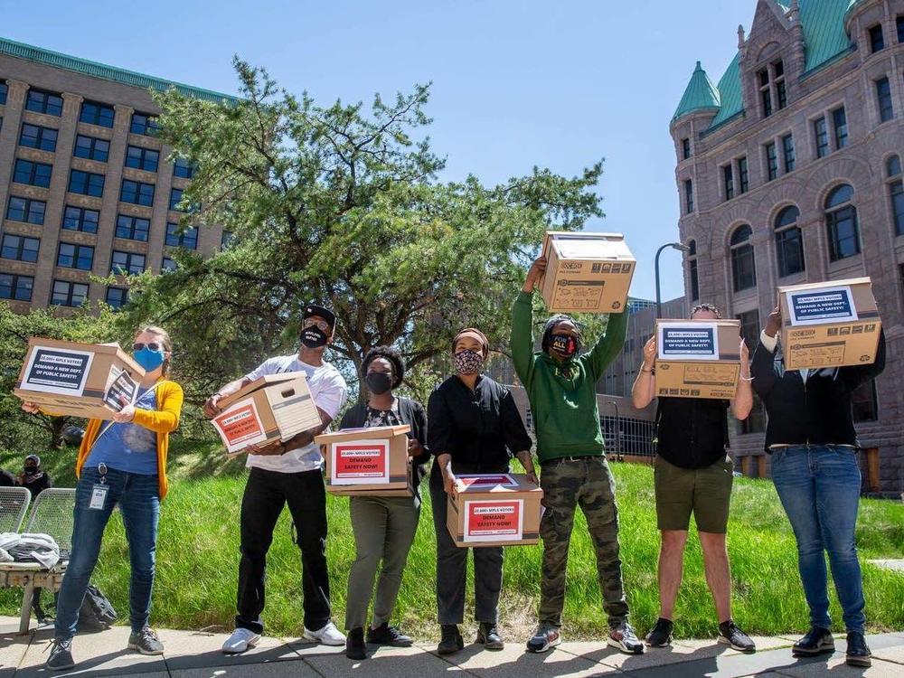 Members of groups making up the Yes 4 Minneapolis coalition hold boxes of petition signatures in the air for a photograph before delivering the signatures to the city clerk in Minneapolis on April 30.