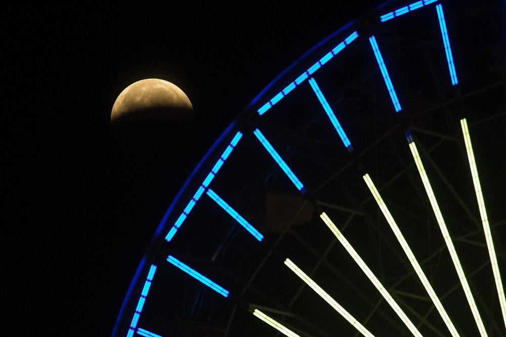 The lunar eclipse progresses behind a Ferris wheel over Santa Monica Beach on Wednesday in Santa Monica, Calif. The first total lunar eclipse in more than two years is coinciding with a supermoon.