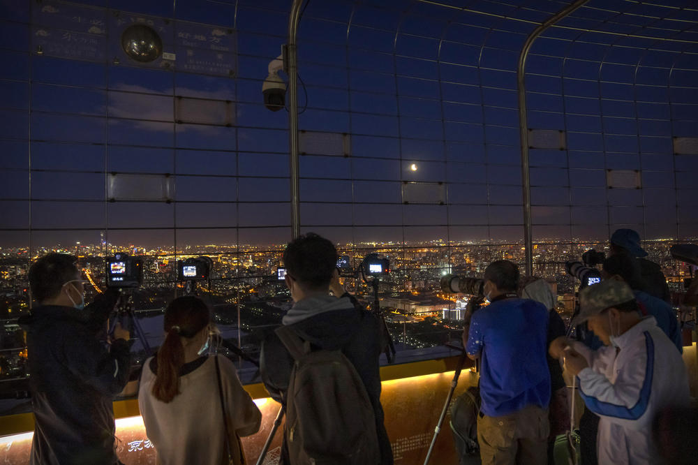 Photographers take photos of the lunar eclipse Wednesday at the Central TV Tower in Beijing.