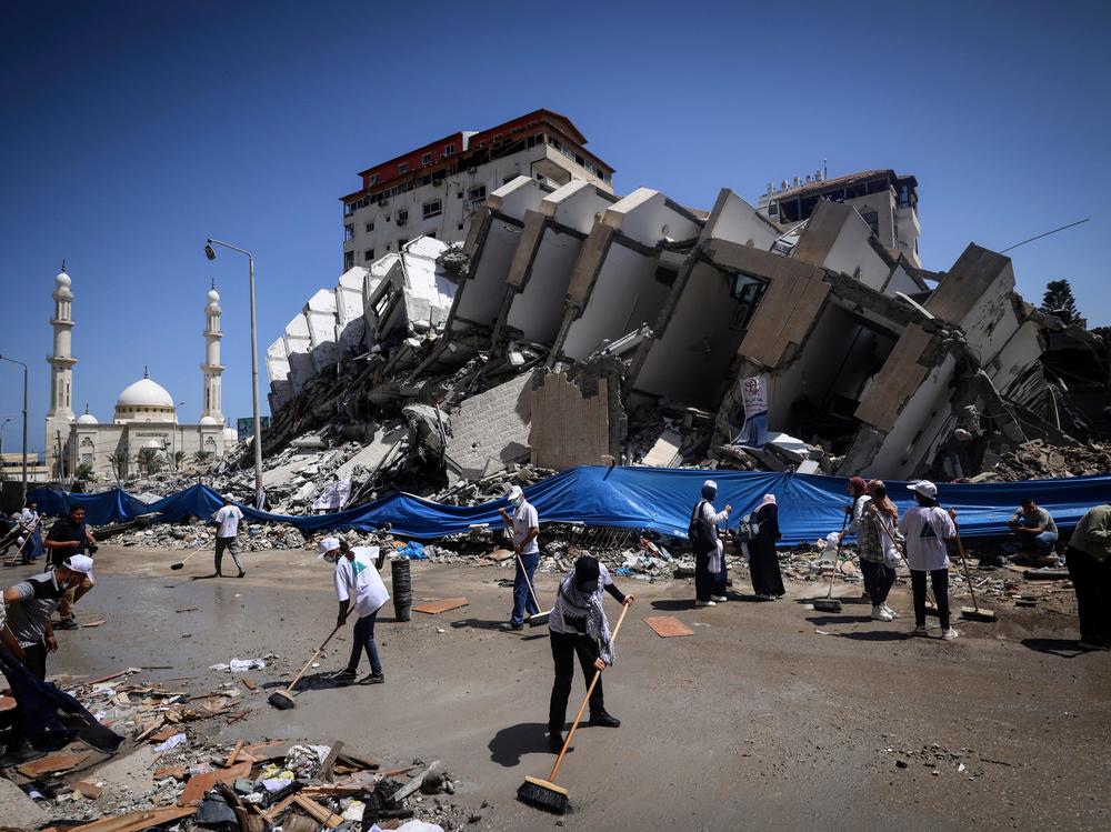 Palestinian volunteers and municipal workers clear the rubble of the Hanadi compound, recently destroyed by Israeli strikes, in Gaza City's Rimal district, on May 25, 2021.
