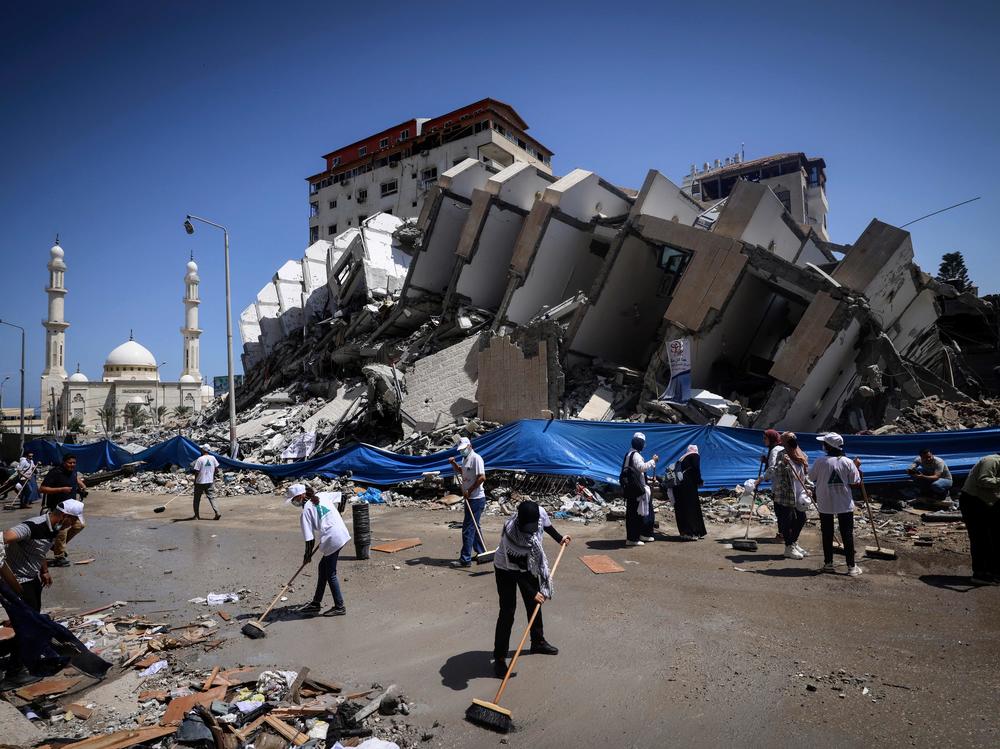Palestinian volunteers and municipal workers clear the rubble of the Hanadi compound, recently destroyed by Israeli strikes, in Gaza City's Rimal district, on May 25, 2021.