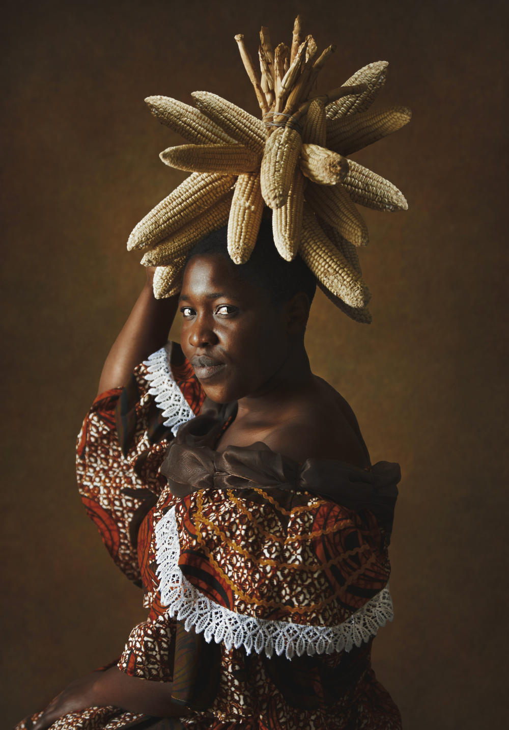 <em>Lady With Corn. </em>Kudita highlights corn in a headdress. A basic grain in Zimbabwe for centuries it still shapes daily meals.