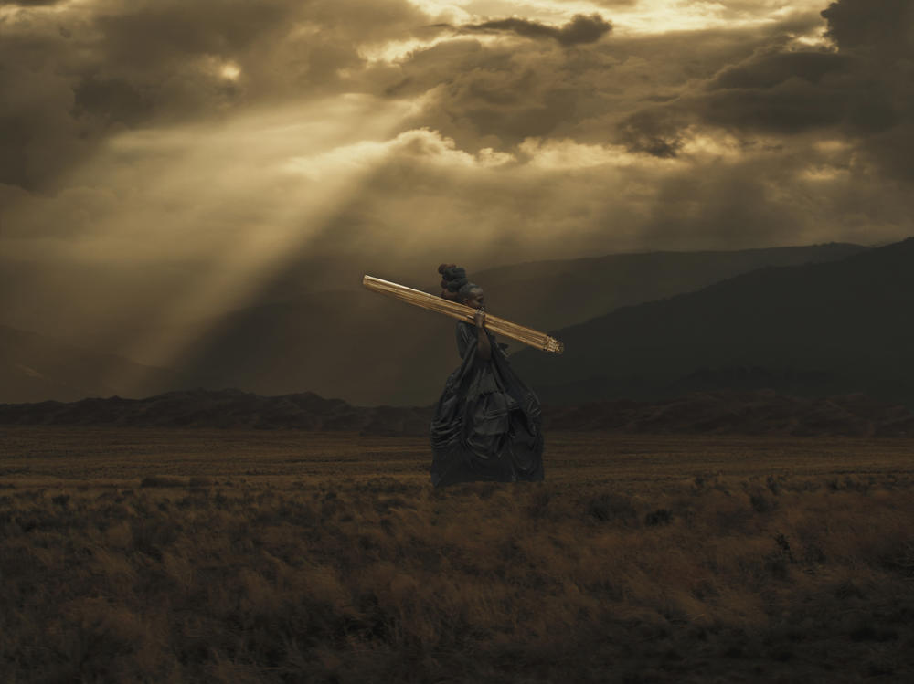 In <em>Rwendo</em>, an African woman in an old-fashioned satin gown traverses a somber landscape.