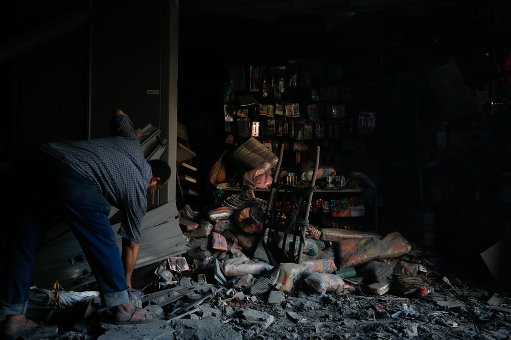 A Palestinian man assesses the damage of his accessories shop the morning after it was damaged.