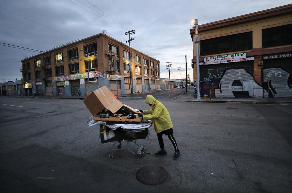 A homeless man pushes his belongings along a Los Angeles street.